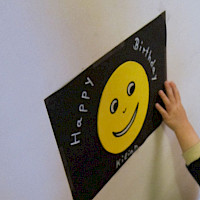 Schwarze Karte mit gelbem Smily  und  weißer Schrift "Happy Birthday"
